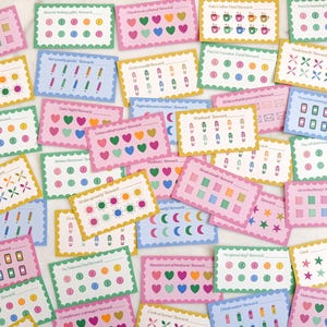 May include: A collection of colorful reward cards with various designs and text. The cards feature scalloped edges and are decorated with hearts, stars, and other shapes. The text on the cards includes phrases like "Date Night Reward" and "Workout Reward".