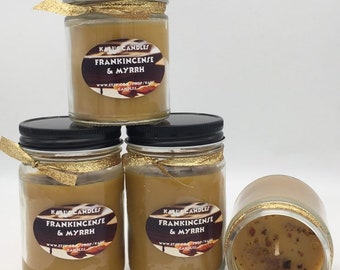 May include: Four amber glass jars with gold lids and gold ribbon accents. Each jar contains a candle with a label that reads "Kalis Candles Frankincense & Myrrh" and a website address.