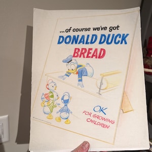 May include: A vintage advertisement for Donald Duck Bread. The illustration features Donald Duck and three ducklings. The text reads "...of course we've got DONALD DUCK BREAD OK FOR GROWING CHILDREN".
