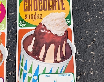Può includere: Un cartello vintage che pubblicizza un sundae al cioccolato. Il cartello presenta un'illustrazione di cartone animato di un sundae al cioccolato con panna montata e salsa al cioccolato in un bicchiere di carta. Il cartello ha uno sfondo giallo con accenti verdi e arancioni. Il testo sul cartello recita "CHOCOLATE sundae" e include i prezzi per i sundae "BIG" e "BIGGEST".