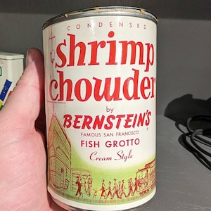 May include: A vintage can of condensed shrimp chowder by Bernstein's Famous San Francisco Fish Grotto. The can is cream style and features a red and green illustration of a building with people walking by.