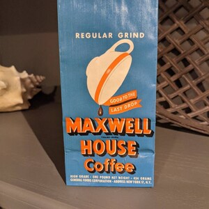 May include: A blue and orange vintage coffee bag with the text "REGULAR GRIND" and "MAXWELL HOUSE Coffee" printed on it. The bag also features a white coffee pot with an orange lid and a drop of coffee dripping from the spout. The text "GOOD TO THE LAST DROP" is printed below the coffee pot.