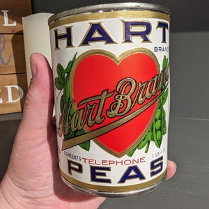 May include: A vintage can of Hart Brand Telephone Peas. The can is white with a red heart and gold lettering. The heart has the words "Hart Brand" in gold script. The can is 1 lb. 4 oz.