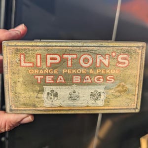 May include: Vintage tin box for Lipton's Orange Pekoe & Pekoe Tea Bags. The box is gold with red and black lettering and features the royal crest.