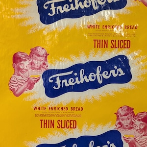 May include: A yellow and blue bag of Freihofer's White Enriched Bread, thin sliced. The bag features a blue and white logo with the text "Freihofer's" in a stylized font. The bag also features a picture of two children holding slices of bread.