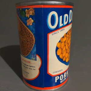 May include: A blue and white can of Old Dutch Pork and Beans with the text "Old Dutch" and "Since 1885" on the label. The can has a picture of beans in a bowl on the front.