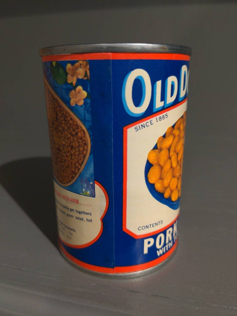 May include: A blue and white can of Old Dutch Pork and Beans with the text "Old Dutch" and "Since 1885" on the label. The can has a picture of beans in a bowl on the front.
