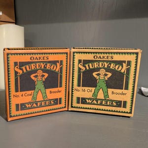 May include: Two vintage boxes with the text "Oakes Sturdy-Boy" and a cartoon figure in green overalls. One box reads "No. 4 Coal Wafers" and the other "No. 16 Oil Wafers". The boxes are orange and black.
