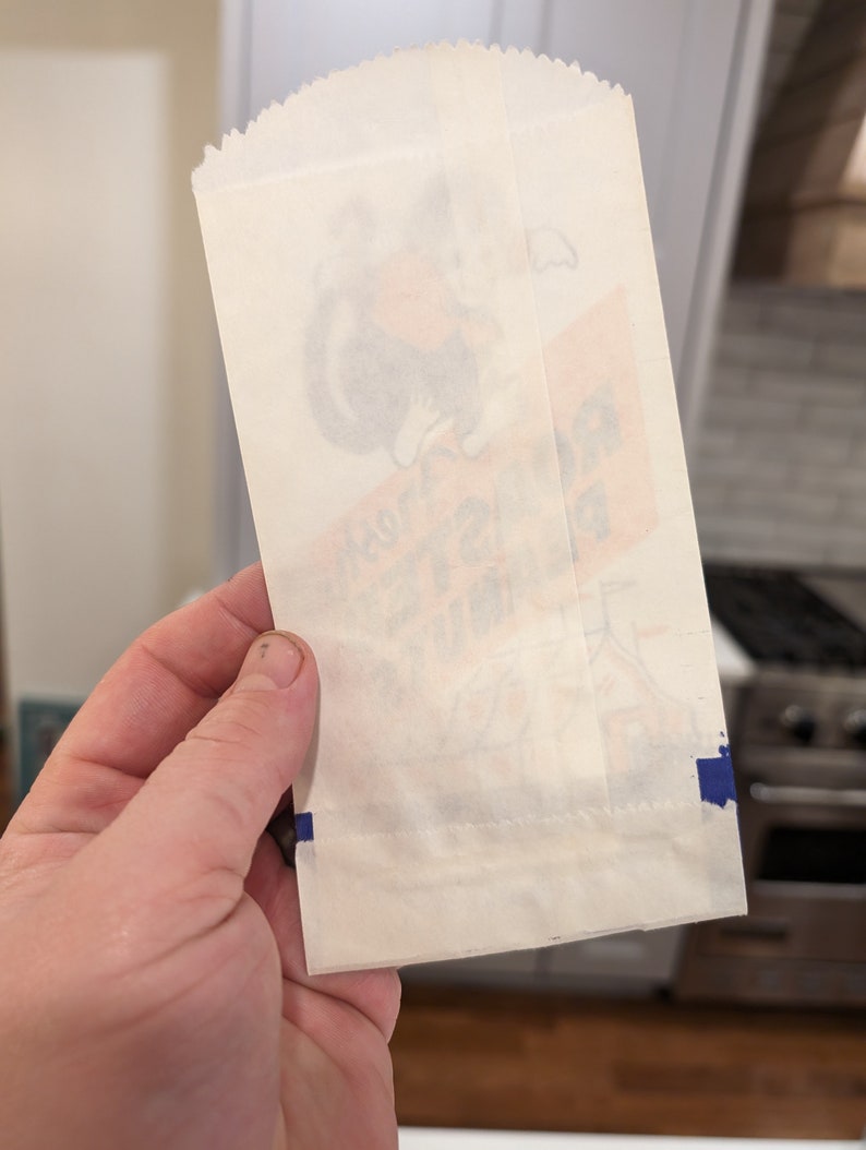 Peut inclure: Un sac en papier blanc avec une bande bleue le long du bord inf&eacute;rieur. Le sac a une image fan&eacute;e d'un personnage de dessin anim&eacute; sur le devant. Le texte sur le sac indique "Joyeux anniversaire".