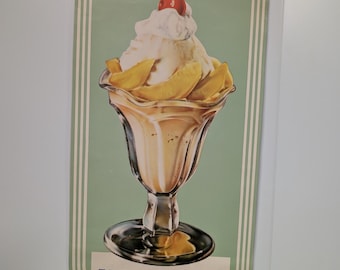 May include: Vintage advertising poster for a Fresh Peach Sundae. The poster features a green background with white stripes and a large illustration of a sundae with a cherry on top. The text "Fresh Peach Sundae" is printed in white with blue lettering.