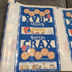 Peut inclure: Une boîte vintage de craquelins Burry's Educator Crax. La boîte est bleue et blanche avec une image d'un lutin souriant tenant une boîte de biscuits au beurre Burry's. La boîte porte le texte "Burry's Educator Crax" et "Donnez de la variété et un goût supplémentaire à vos soupes, salades, cocktails, boissons chaudes".