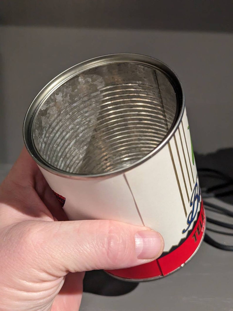 May include: Empty metal can with a white label and red trim. The label has black and green text that reads "Telluride Brewing Company" and a graphic of a mountain range.