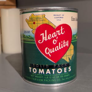May include: Vintage Heart o' Quality solid pack tomatoes can. The label features a red heart with the text "Heart o' Quality" and a map of California. The can weighs 1 lb. 12 oz. or 795 grams.