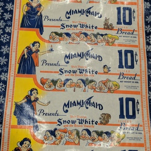 May include: Vintage Miami Maid bread wrapper featuring Snow White and the Seven Dwarfs. The wrapper has illustrations of Snow White and the dwarfs, along with the text "SLICED Bread" and "10¢". The wrapper is yellow, white, and blue.