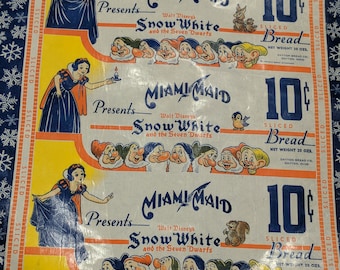 May include: Vintage Miami Maid bread wrapper featuring Snow White and the Seven Dwarfs. The wrapper has illustrations of Snow White and the dwarfs, along with the text "SLICED Bread" and "10¢". The wrapper is yellow, white, and blue.