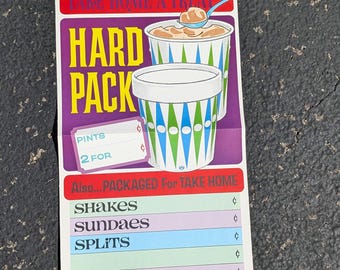 Può includere: Un cartello vintage che pubblicizza il gelato con il testo "Take Home A Treat Hard Pack" e un listino prezzi per frullati, gelati e split.