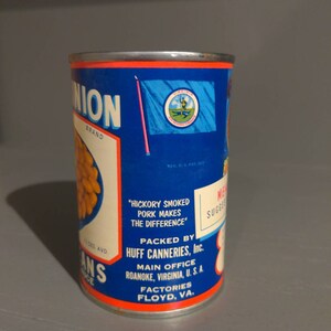 May include: A blue and red can of Union brand canned beans. The can has a label with the text "Hickory Smoked Pork Makes The Difference" and "Packed by Huff Canneries, Inc.". The label also includes the company's main office location in Roanoke, Virginia, U.S.A. and factory location in Floyd, Virginia.