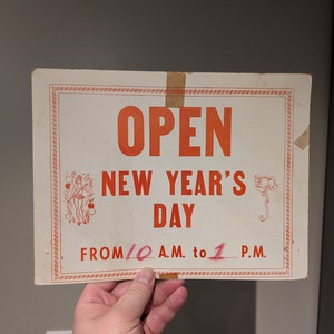 Letrero de cartón original de los años 40 con el horario de apertura de la tienda el día de Año Nuevo - Vintage