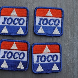 May include: Four square patches with the word "IOCO" in white letters on a blue background. The patches have a red, white, and blue color scheme with a white triangle at the top and two white triangles at the bottom.