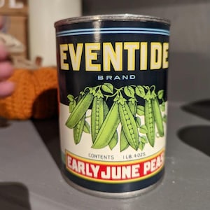May include: A vintage Eventide brand can of Early June Peas. The can features a black background with yellow text and a graphic of green pea pods. The can's contents are 1 lb. 4 oz.