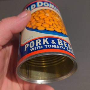 May include: A vintage can of Old Dominion Pork & Beans with Tomato Sauce. The can is open and the beans are visible inside. The can is blue, red, and white with the words "Old Dominion" and "Pork & Beans with Tomato Sauce" printed on it.