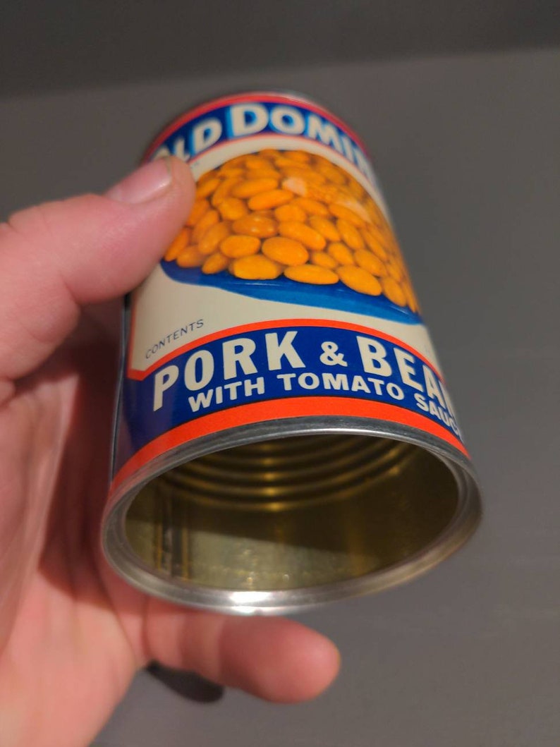May include: A vintage can of Old Dominion Pork & Beans with Tomato Sauce. The can is open and the beans are visible inside. The can is blue, red, and white with the words "Old Dominion" and "Pork & Beans with Tomato Sauce" printed on it.