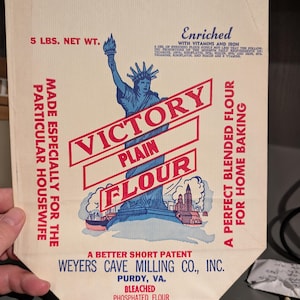 May include: Vintage Victory Plain Flour bag with a blue Statue of Liberty illustration and red text. The bag reads "5 LBS. NET WT." and "Made Especially for the Particular Housewife."