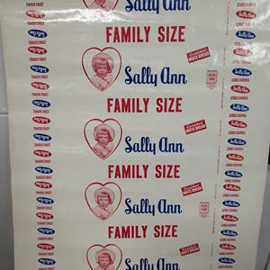 May include: A vintage paper roll featuring the "Sally Ann" brand, with the words "Family Size" in red. The design includes a heart-shaped portrait of a young girl. The words "Tender Crust" are also visible.