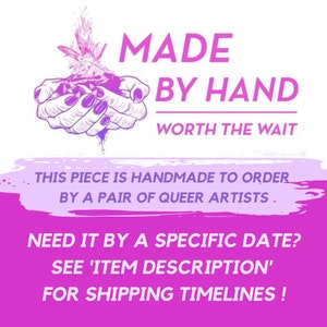 May include: A graphic design with the text "MADE BY HAND WORTH THE WAIT." The image features a pair of hands holding a design with a purple and pink color scheme. The text also includes "THIS PIECE IS HANDMADE TO ORDER BY A PAIR OF QUEER ARTISTS."