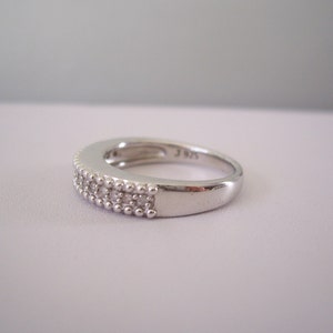 May include: A silver band ring with a double row of small clear stones.