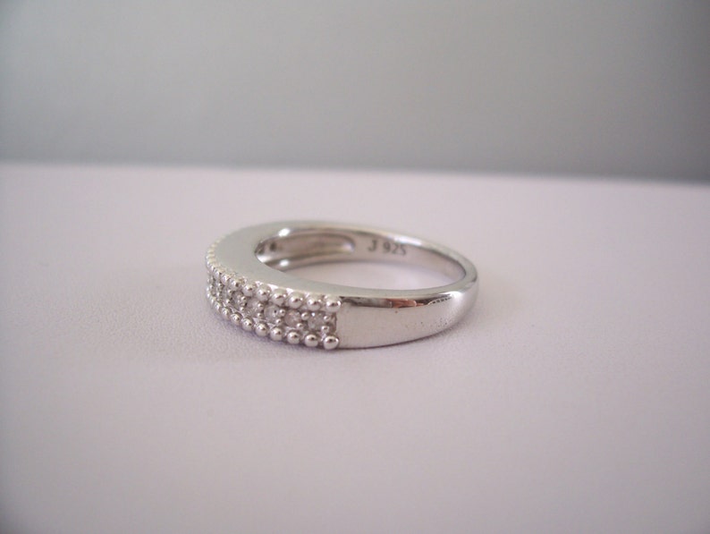 May include: A silver band ring with a double row of small clear stones.