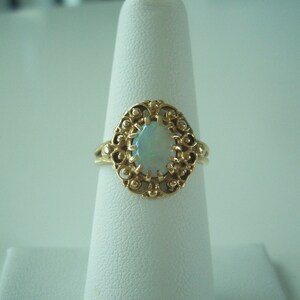 May include: A gold ring with an oval opal gemstone set in a filigree design.