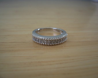 May include: A silver band ring with a double row of small, clear stones.