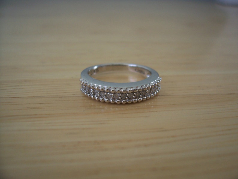 May include: A silver band ring with a double row of small, clear stones.