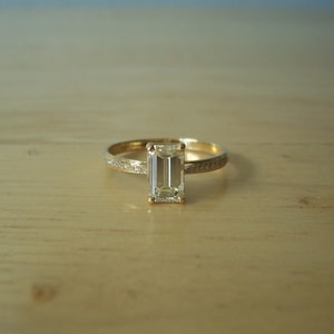 May include: A gold ring with a clear emerald-cut diamond.