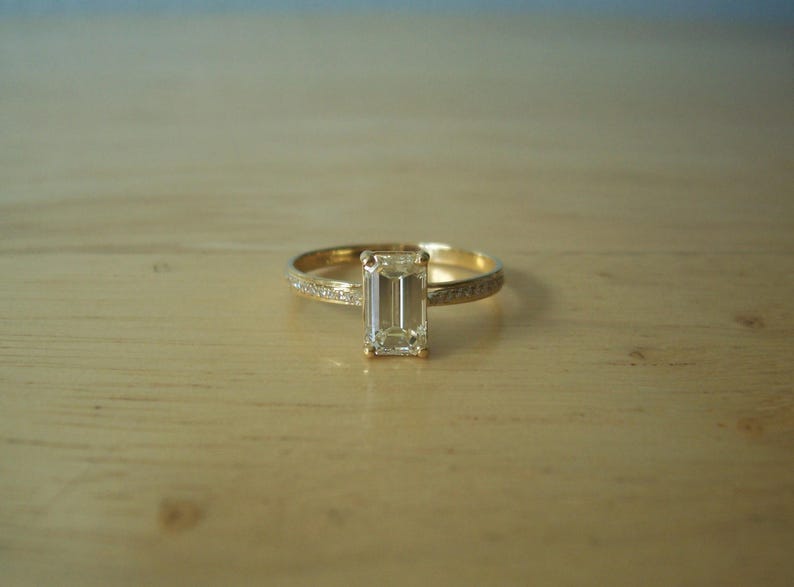 May include: A gold ring with a clear emerald-cut diamond.