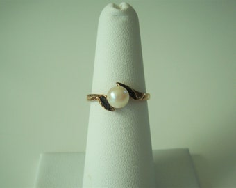 May include: A gold ring with a single pearl set in a leaf design.