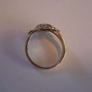 May include: A gold ring with a white stone set in a decorative design.