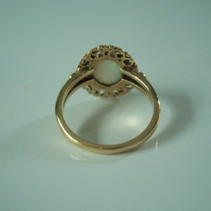 May include: A gold ring with a white opal stone set in a filigree design.