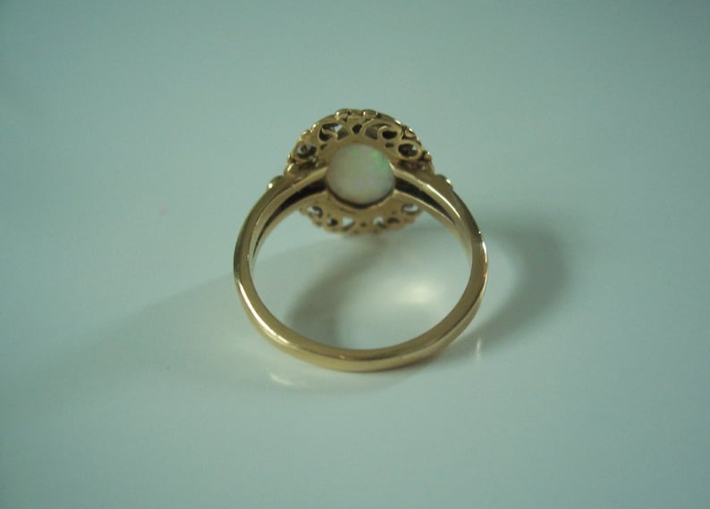 May include: A gold ring with a white opal stone set in a filigree design.
