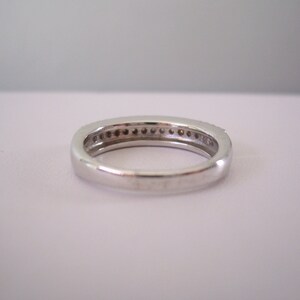 May include: A silver band ring with a row of small diamonds set in the band.