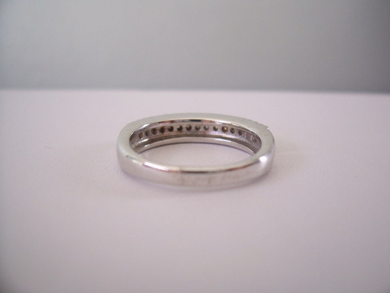 May include: A silver band ring with a row of small diamonds set in the band.