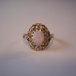May include: A gold ring with an opal gemstone set in a delicate filigree design.