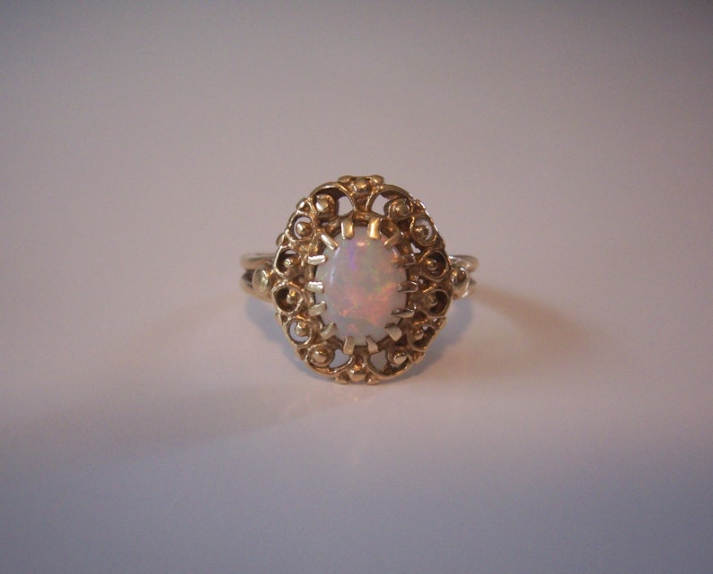 May include: A gold ring with an opal gemstone set in a delicate filigree design.