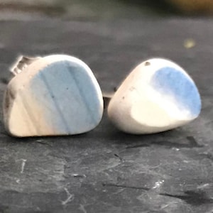 Könnte beinhalten: Ein Paar kleine, weiße und blaue Keramikohrringe. Die Ohrringe haben die Form einer Träne und eine glatte, polierte Oberfläche.
