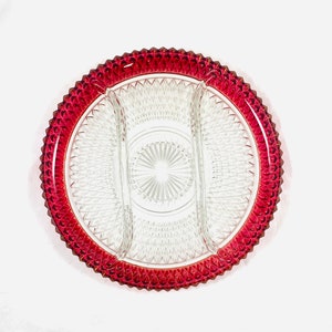 May include: A clear glass serving dish with three sections, featuring a diamond pattern and a red rim.