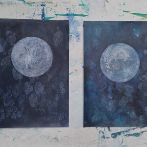 May include: Two abstract paintings of a white moon on a dark blue background. The moon is surrounded by white shapes that resemble leaves or clouds.