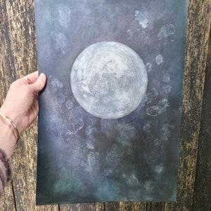 May include: A watercolor painting of a full moon in a dark blue sky with white speckles. The moon is painted in shades of gray and white.