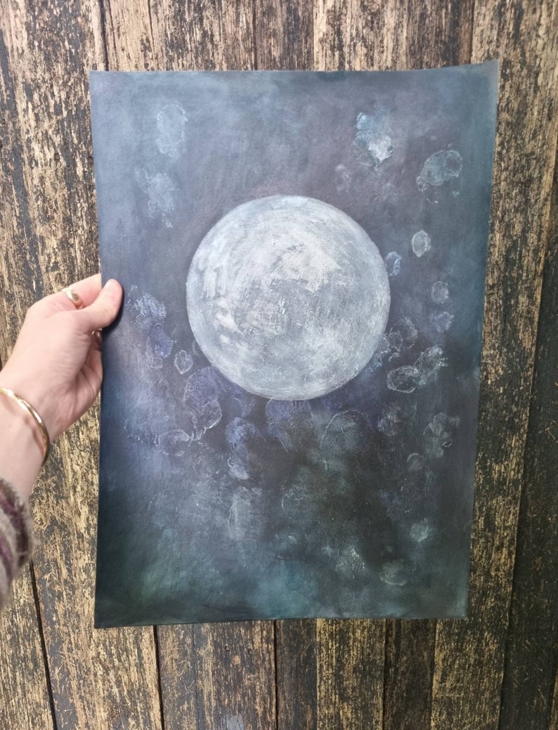 May include: A watercolor painting of a full moon in a dark blue sky with white speckles. The moon is painted in shades of gray and white.