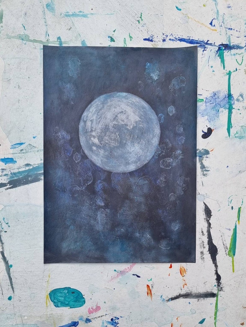 May include: A painting of a large, white moon on a dark blue background with white speckles. The moon is in the center of the painting and is the main focus.